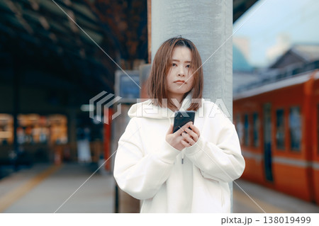 駅のホームでスマホを操作する女性 駅のホームでスマホを操作する女性 138019499