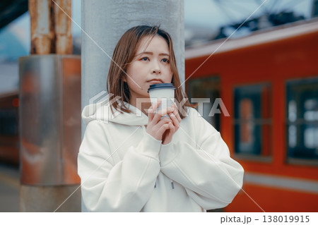 駅ホームでコーヒーを持つ20代女性のポートレート 138019915