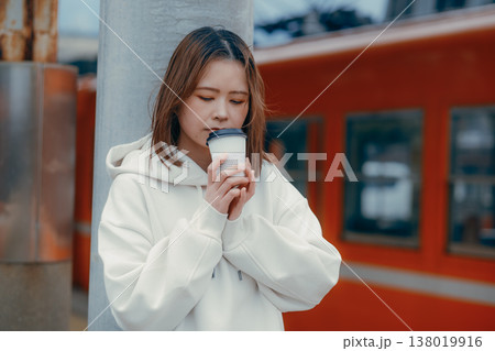 駅ホームでコーヒーを持つ20代女性のポートレート 駅ホームでコーヒーを持つ20代女性のポートレート 138019916