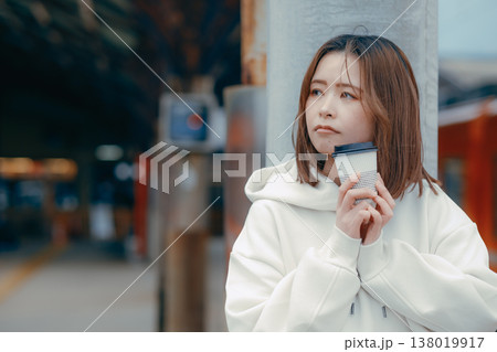 駅ホームでコーヒーを持つ20代女性のポートレート 138019917