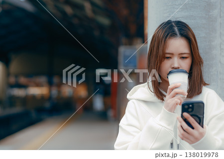 駅ホームでコーヒーを持つ20代女性のポートレート 138019978
