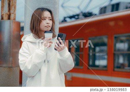 駅ホームでコーヒーを持つ20代女性のポートレート 138019983