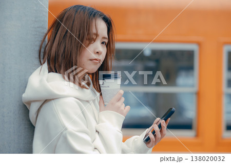 駅ホームでコーヒーを持つ20代女性のポートレート 駅ホームでコーヒーを持つ20代女性のポートレート 138020032