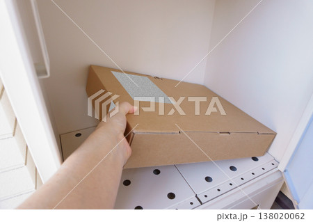 宅配ボックスの荷物を取り出す手元 138020062