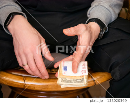 Man holding stack of cash with euro and dollar bank notes. Wealth and investment concept. Person managing personal finance, savings, or business payment. Financial transaction and economy. Man holding stack of cash with euro and dollar bank notes. Wealth and investment concept. Person managing personal finance, savings, or business payment. Financial transaction and economy. 138020569