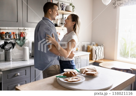 Couple embracing and laughing during romantic morning in kitchen 138021116