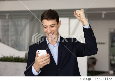 Businessman read message on phone, feeling overjoyed, celebrate professional success Businessman read message on phone, feeling overjoyed, celebrate professional success 138021122