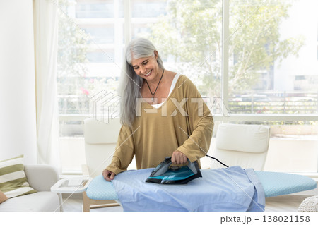 Smiling woman smoothing-out husband shirt with iron Smiling woman smoothing-out husband shirt with iron 138021158