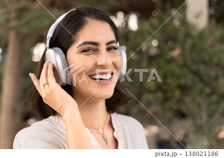Positive beautiful Latin woman in wireless headphones looking at camera 138021186