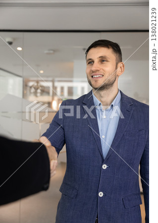 Confident young businessman dressed in suit shaking hands with client Confident young businessman dressed in suit shaking hands with client 138021239