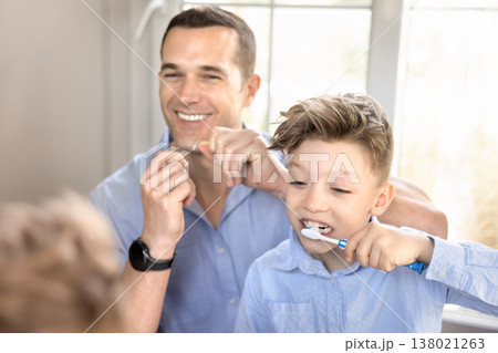 Father using dental floss, child brushing teeth 138021263