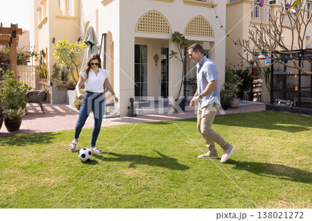 Married couple playing football in backyard of country house 138021272