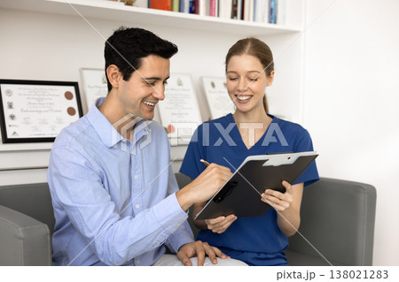 Patient holding pen and signing agreement during visit in clinic Patient holding pen and signing agreement during visit in clinic 138021283