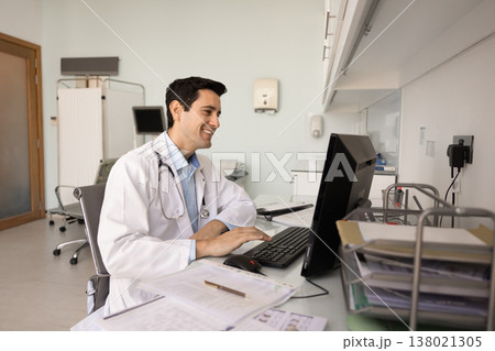 Smiling doctor working at computer in medical office Smiling doctor working at computer in medical office 138021305