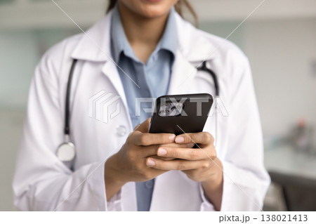 Closeup cropped image of female doctor in coat holding smartphone 138021413