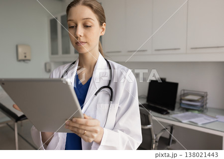Serious Argentinian nurse working on tablet device in clinic office 138021443