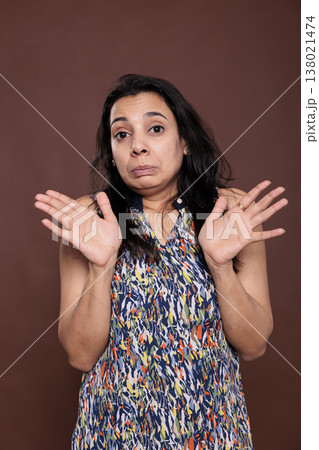 Indian woman showing no problem gesture with palms, slow down, looking at camera. Young person standing with spread arms portrait, okay sign, front view studio medium shot on brown background Indian woman showing no problem gesture with palms, slow down, looking at camera. Young person standing with spread arms portrait, okay sign, front view studio medium shot on brown background 138021474