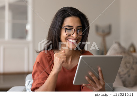 Happy Latina woman reading great, incredible news on tablet Happy Latina woman reading great, incredible news on tablet 138021511