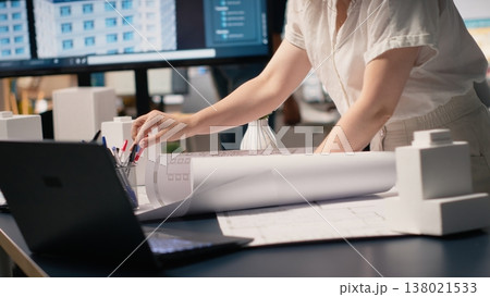 Female contractor measuring the construction site layout with blueprints to create the residential project master plan. Setting infrastructure goals on sustainability and prepares pitch. 138021533