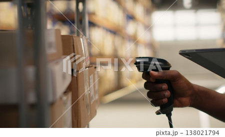 Close up of logistics staff scanning airway bill tags for inventory registration, updating records in import export system on tablet. Retail e-commerce operations in industrial depot. Camera B. Close up of logistics staff scanning airway bill tags for inventory registration, updating records in import export system on tablet. Retail e-commerce operations in industrial depot. Camera B. 138021794