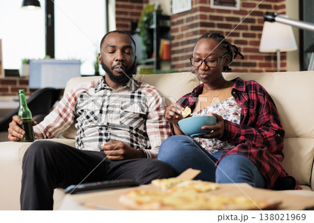 Relaxed people eating chips from bowl and drinking beer, having fun together with fast food takeaway meal. Enioying takeout delivery and watching movie or film on television, entertainment. Relaxed people eating chips from bowl and drinking beer, having fun together with fast food takeaway meal. Enioying takeout delivery and watching movie or film on television, entertainment. 138021969