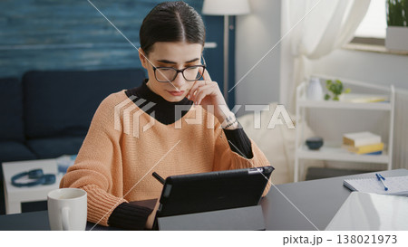 University student taking notes on digital tablet with stylus, using gadget to learn educational course for online school class. Woman working on device to prepare for remote homework lesson. University student taking notes on digital tablet with stylus, using gadget to learn educational course for online school class. Woman working on device to prepare for remote homework lesson. 138021973
