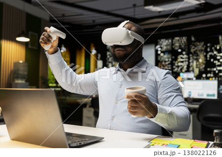 Black male employee using virtual reality glasses to draft a plan for goals, forecasting projections and documenting risk assessment. Organizing agenda to align with business objectives. Black male employee using virtual reality glasses to draft a plan for goals, forecasting projections and documenting risk assessment. Organizing agenda to align with business objectives. 138022126