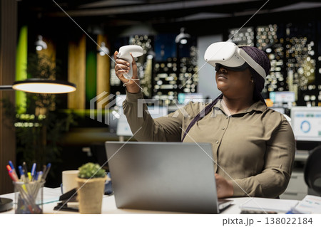 Female employee using VR glasses and gadgets to draft a project plan, engaged in forecasting projections and documenting risk assessment results. Organizing tasks to align with business goals. Female employee using VR glasses and gadgets to draft a project plan, engaged in forecasting projections and documenting risk assessment results. Organizing tasks to align with business goals. 138022184