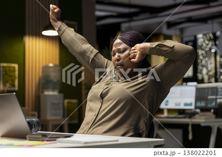 Drained restless woman yawning and stretching her back muscles, going into mental haze and weariness with late night work. Employee in discomfort feeling anxious and overwhelmed. Drained restless woman yawning and stretching her back muscles, going into mental haze and weariness with late night work. Employee in discomfort feeling anxious and overwhelmed. 138022201