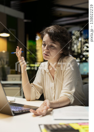 Female employee strategizing and focusing on logical solutions and ideas for development, reflecting on options and tactics doing overtime at night. Employee engaging in critical thinking. 138022219