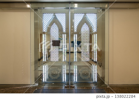 Symmetrical glass entrance with Islamic geometric patterns and arch design in modern building. Symmetrical glass entrance with Islamic geometric patterns and arch design in modern building. 138022284