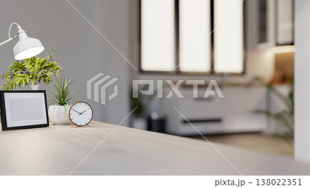 Photo frame with clock and lamp aside pot plant on wooden table across window in modern living room. 138022351