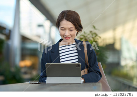 屋外でタブレットを使って仕事をする30代日本人ビジネスウーマン 138022795