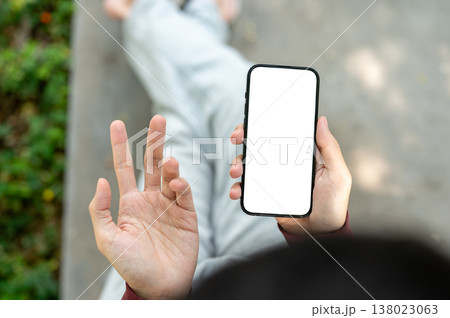 Top view close up of hand holding white screen phone and confused hand while sitting over sidewalk. 138023063