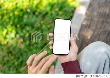 Top view close up of hand holding white screen phone and fingers hovering as sitting at garden park. Top view close up of hand holding white screen phone and fingers hovering as sitting at garden park. 138023064