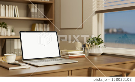 White screen laptop with coffee on wooden table aside bookshelf and window with sea view in office. White screen laptop with coffee on wooden table aside bookshelf and window with sea view in office. 138023108