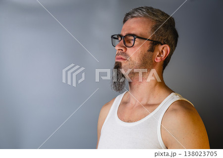 Man stands still with closed eyes in a simple tank top and glasses 138023705
