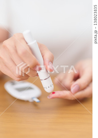 Hand using lancet pen on finger with Blood drop glucose testing or Diabetes checking by digital blood glucose meter. blood sugar level, Diabetes Day, Glycemia, Hypoglycemia, Hyperglycemia and insulin 138023835