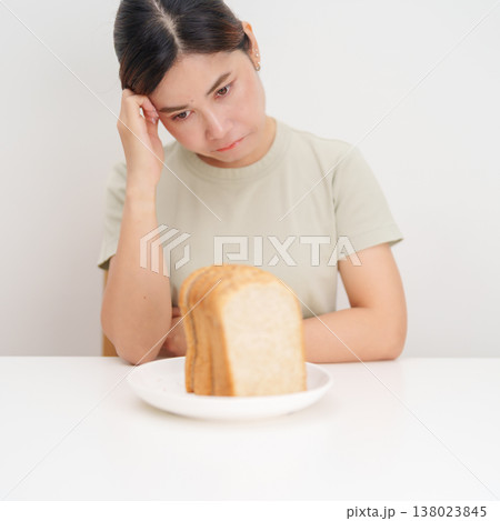 Unhappy woman disgust gesture and Bored to eat bread. concept of gluten intolerance, gluten sensitivity, carb loading concerns, or a disliking for unhealthy dietary habits Unhappy woman disgust gesture and Bored to eat bread. concept of gluten intolerance, gluten sensitivity, carb loading concerns, or a disliking for unhealthy dietary habits 138023845