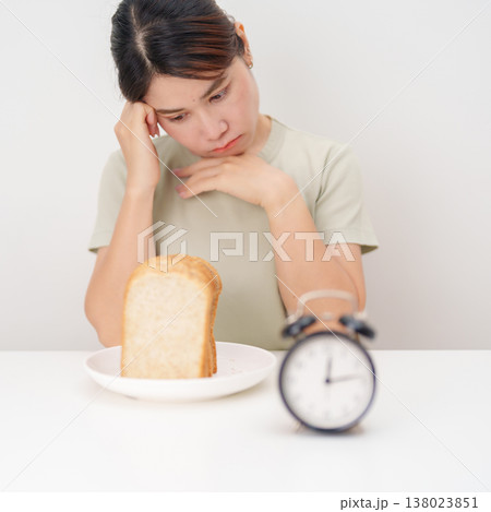 hungry woman with whole wheat bread and clock. concept of intermittent fasting, IF, meal, Time to eat, choosing healthy carbohydrates, balanced diet and weight loss management, Nutrition schedule hungry woman with whole wheat bread and clock. concept of intermittent fasting, IF, meal, Time to eat, choosing healthy carbohydrates, balanced diet and weight loss management, Nutrition schedule 138023851