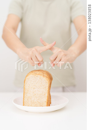 Unhappy woman showing Rejecting gesture and refusing to eat bread. concept of gluten intolerance, gluten sensitivity, carb loading concerns, or a disliking for unhealthy dietary habits 138023858
