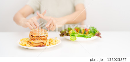 woman showing Rejecting and refusing with Hamburger. Healthy and Unhealthy Food Choice, Calories and Nutrition of vegetables Salad and Hamburger. dieting, weight loss, junk food and lifestyle woman showing Rejecting and refusing with Hamburger. Healthy and Unhealthy Food Choice, Calories and Nutrition of vegetables Salad and Hamburger. dieting, weight loss, junk food and lifestyle 138023875