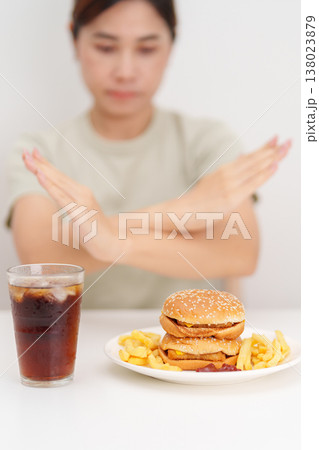 Unhappy woman showing Rejecting and refusing with Juicy beef burger, potato chips and carbonated Soft drinks. Unhealthy, High calorie, Fast food craving, Obesity, diet, weight loss and junk food Unhappy woman showing Rejecting and refusing with Juicy beef burger, potato chips and carbonated Soft drinks. Unhealthy, High calorie, Fast food craving, Obesity, diet, weight loss and junk food 138023879