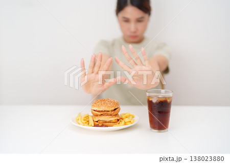 Unhappy woman showing Rejecting and refusing with Juicy beef burger, potato chips and carbonated Soft drinks. Unhealthy, High calorie, Fast food craving, Obesity, diet, weight loss and junk food Unhappy woman showing Rejecting and refusing with Juicy beef burger, potato chips and carbonated Soft drinks. Unhealthy, High calorie, Fast food craving, Obesity, diet, weight loss and junk food 138023880