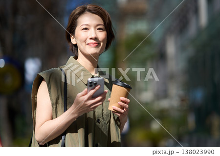 スマートフォンを手に街を歩く30代日本人女性 138023990