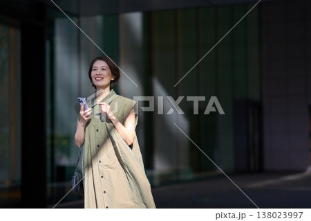 スマートフォンを手に街を歩く30代日本人女性 138023997