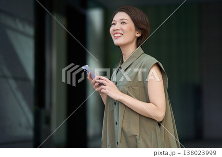 スマートフォンを手に街を歩く30代日本人女性 138023999