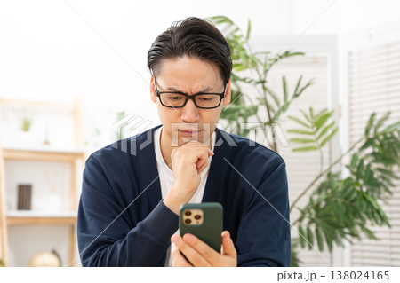 スマホを見て悩む男性 ショック スマホを見て悩む男性 ショック 138024165