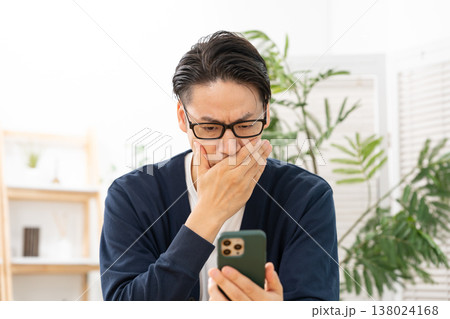 スマホを見て悩む男性　ショック 138024168
