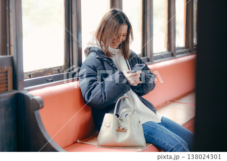 電車内でスマホを操作する20代女性のポートレート 138024301